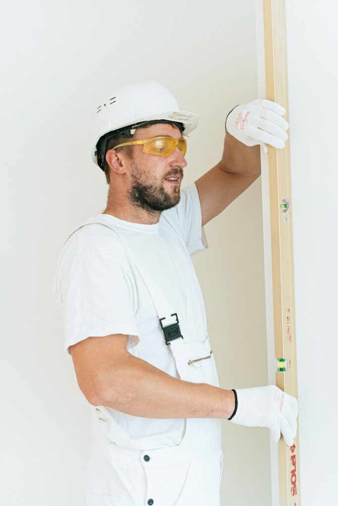 pexels-photo-4981778 Carpenter in safety gear using a level bar indoors for precise construction work.